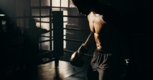 Silhouetted male boxer trains with dramatic lighting, emphasizing strength and focus.